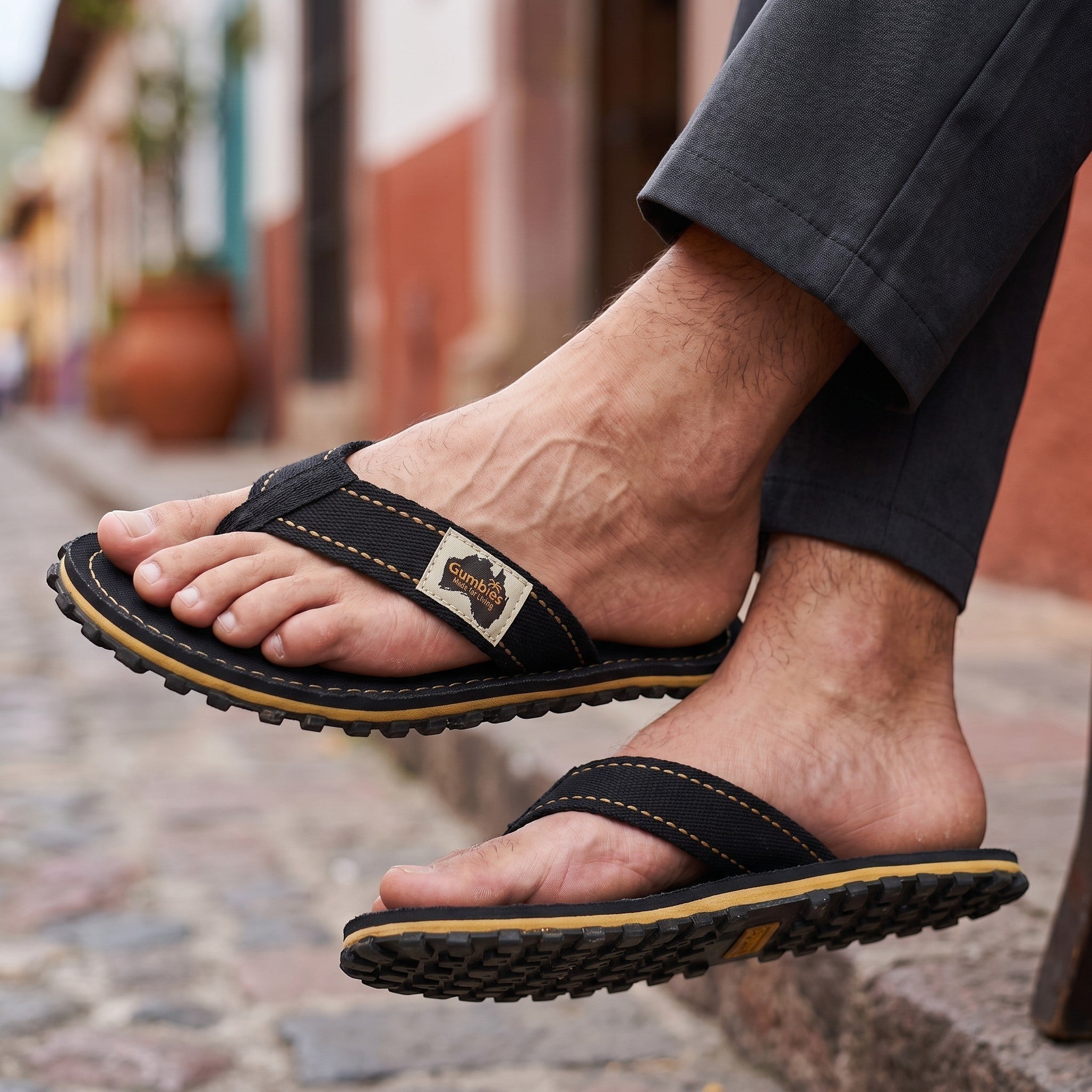 GUMBIES FRANCE Classic Black canvas flip-flops with tan stitching and a textured rubber sole.