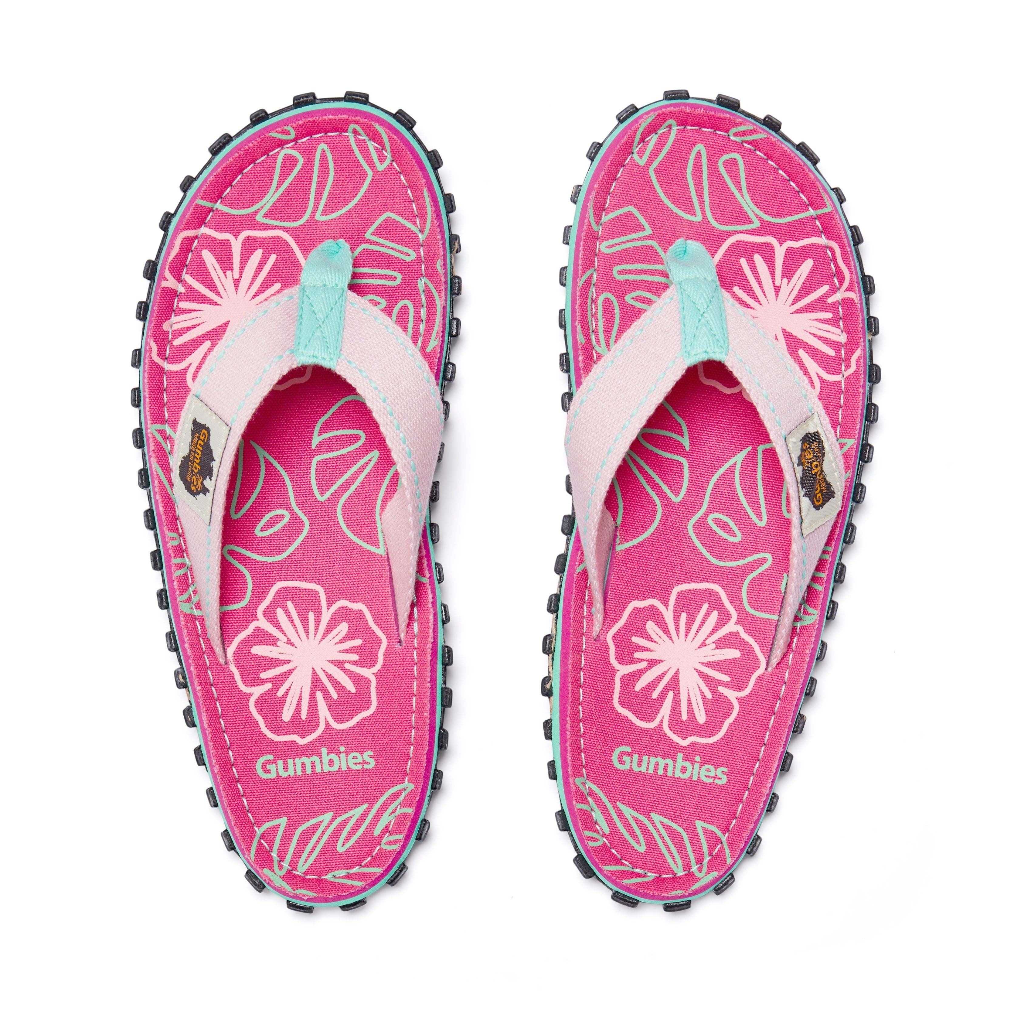 GUMBIES FRANCE Islander flip-flops in pink with a hibiscus and leaf print, light pink straps, and a teal trim.